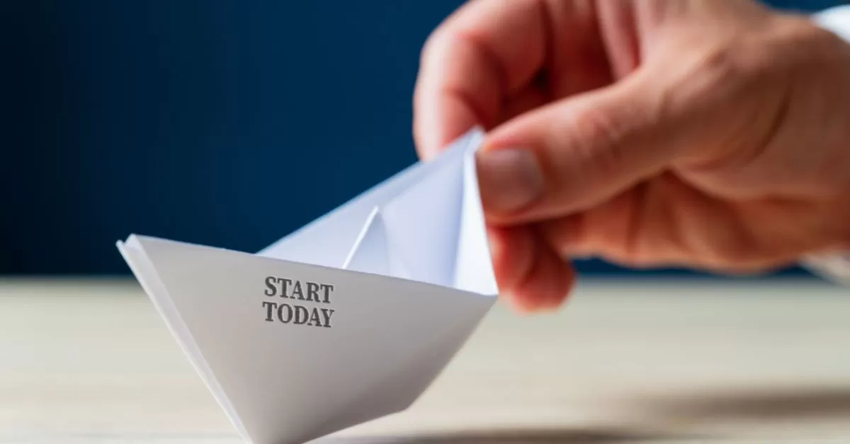 a hand holding a paper boat, with text "start today" printed on the boat